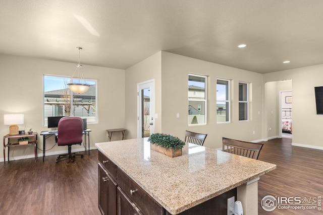 kitchen with baseboards, light stone countertops, dark wood finished floors, dark brown cabinetry, and decorative light fixtures