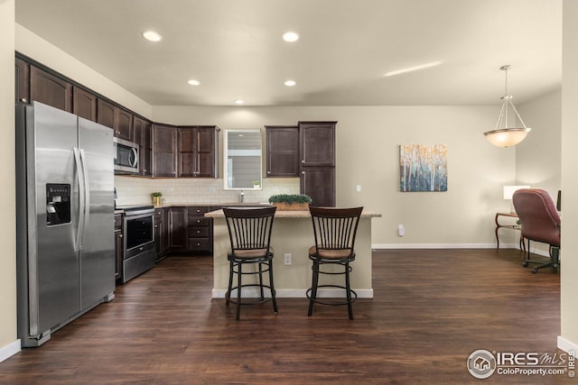 kitchen with a breakfast bar, backsplash, dark wood-style floors, stainless steel appliances, and dark brown cabinets