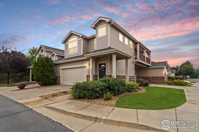 view of front of property featuring brick siding, a balcony, concrete driveway, and a garage