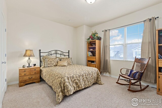 bedroom with light colored carpet and baseboards