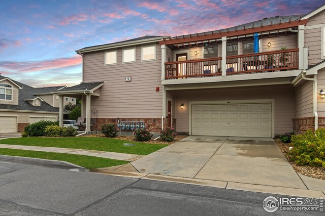 view of front facade with driveway, brick siding, an attached garage, and a balcony