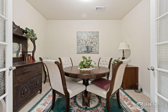 dining room featuring visible vents, light colored carpet, french doors, and baseboards