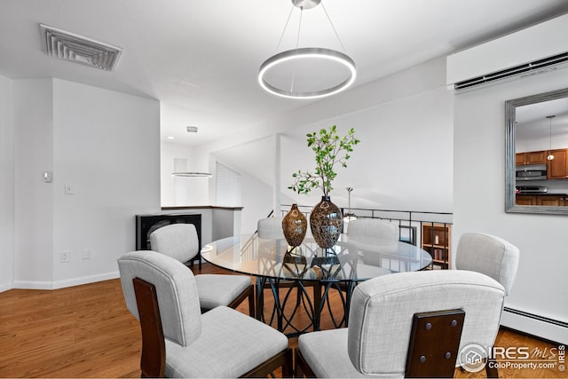 dining space with visible vents, wood finished floors, baseboards, and a baseboard radiator