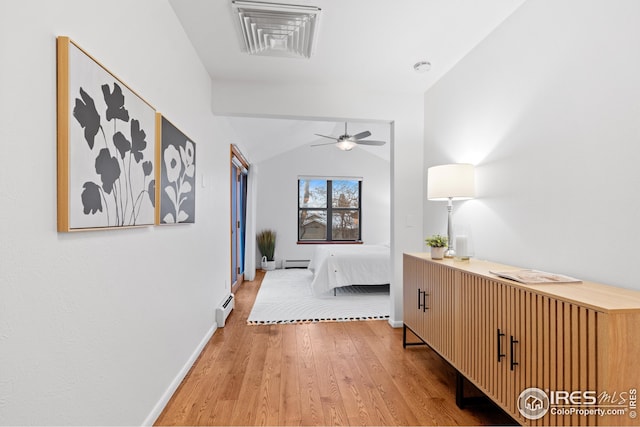 hallway with light wood finished floors, baseboards, vaulted ceiling, baseboard heating, and a baseboard radiator