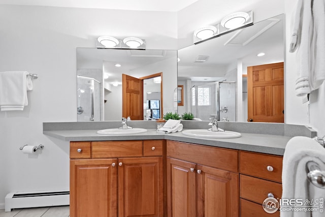 bathroom featuring a baseboard heating unit, a shower stall, double vanity, and a sink