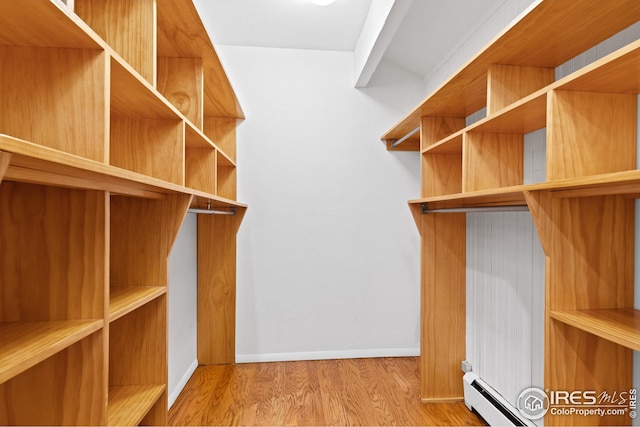 walk in closet featuring a baseboard radiator, wood finished floors, and a baseboard heating unit