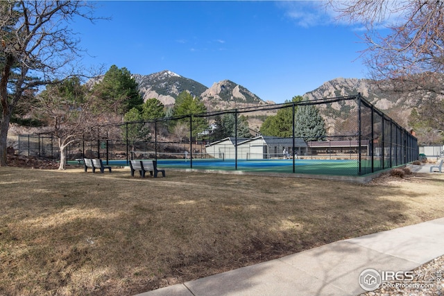 view of sport court with a yard, fence, and a mountain view