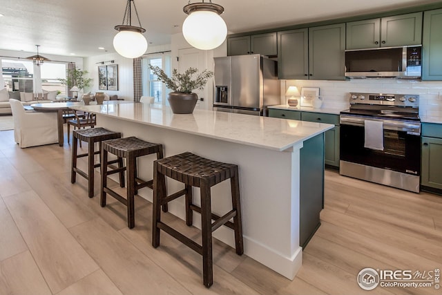 kitchen featuring decorative backsplash, light stone countertops, light wood-style floors, and stainless steel appliances