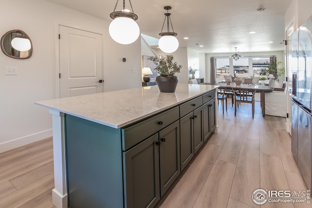 kitchen with light wood-style flooring, light stone counters, open floor plan, and a kitchen island