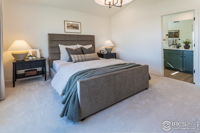 carpeted bedroom featuring baseboards, an inviting chandelier, ensuite bath, and vaulted ceiling