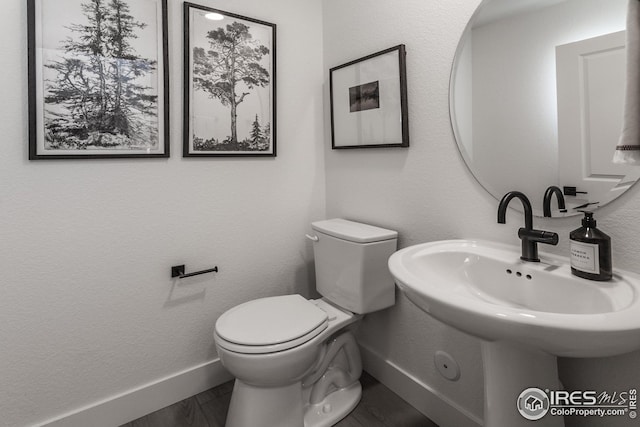 half bath with toilet, baseboards, and a textured wall