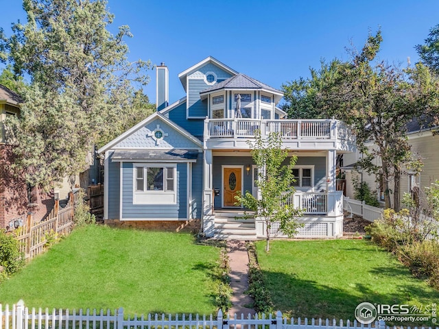 victorian house with a chimney, a balcony, fence private yard, and a front lawn