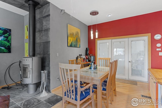 dining space featuring a wood stove, french doors, light wood-style floors, and baseboards
