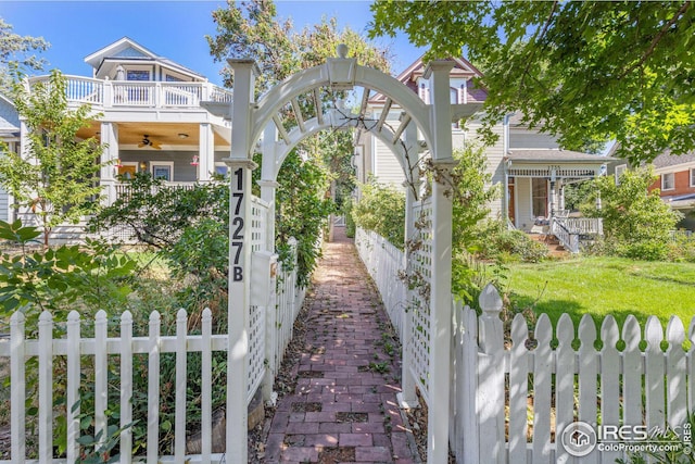 exterior space with a fenced front yard, a front lawn, a balcony, and a gate