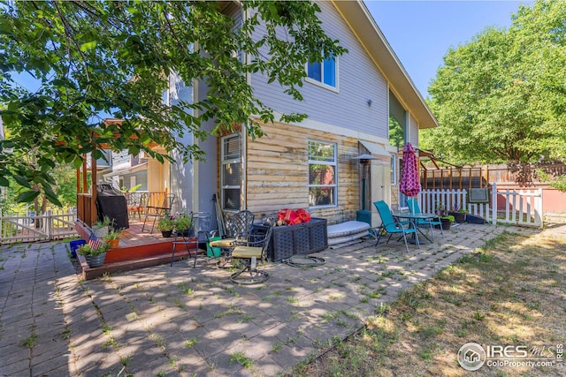 rear view of house featuring a patio area, a wooden deck, and fence