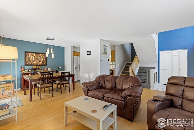 living area featuring light wood-type flooring, baseboards, and stairway