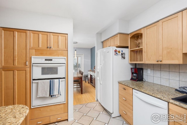 kitchen with light brown cabinets, light stone counters, tasteful backsplash, white appliances, and light tile patterned floors