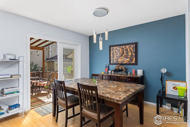 dining area with baseboards and light wood finished floors