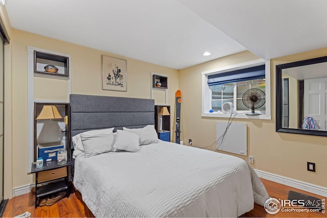 bedroom featuring recessed lighting, a baseboard heating unit, baseboards, and wood finished floors