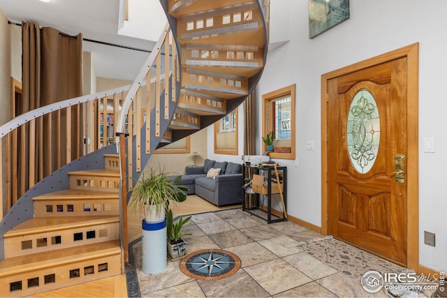 entryway featuring stairway, stone finish floor, and baseboards