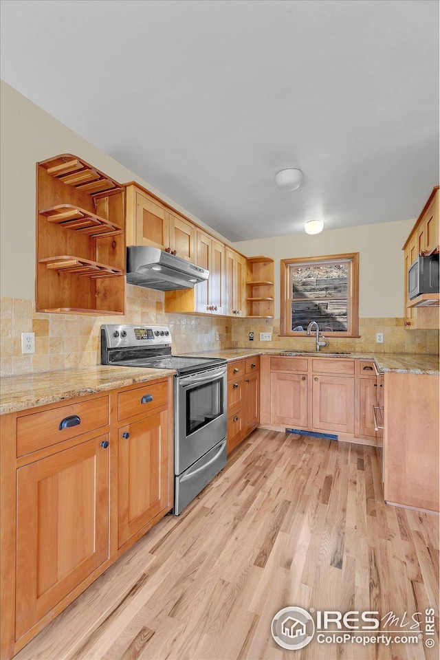 kitchen with light stone counters, under cabinet range hood, open shelves, stainless steel appliances, and a sink