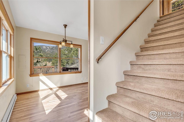stairs with a baseboard radiator, wood finished floors, and baseboards