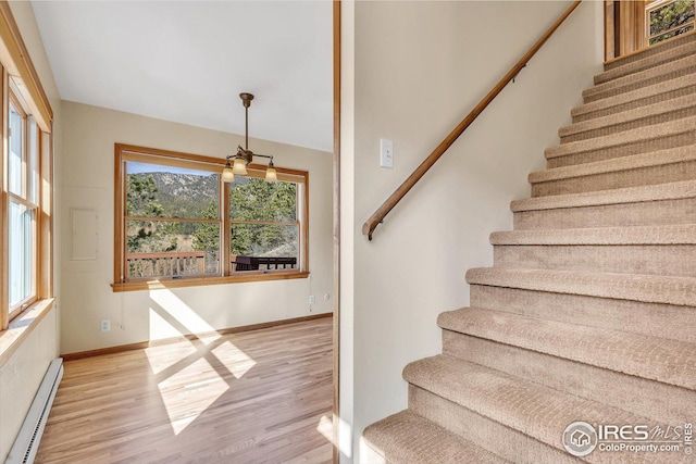 stairway featuring baseboard heating, baseboards, and wood finished floors