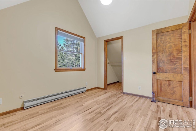 unfurnished bedroom featuring lofted ceiling, a spacious closet, light wood-type flooring, baseboards, and baseboard heating