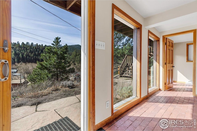 doorway to outside featuring brick floor and baseboards