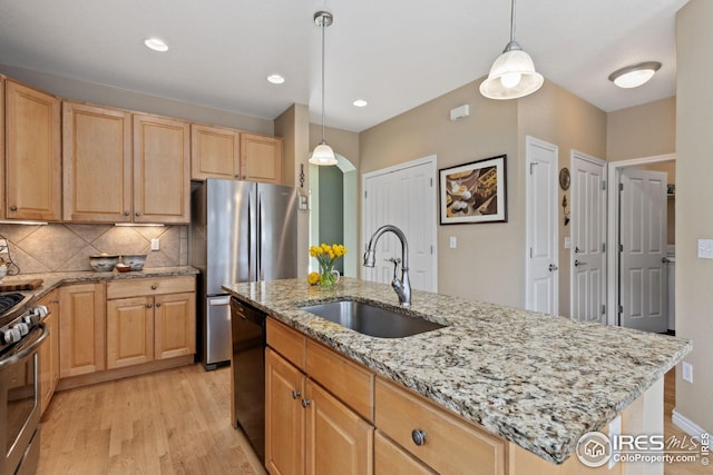 kitchen with light brown cabinetry, light wood-type flooring, appliances with stainless steel finishes, and a sink