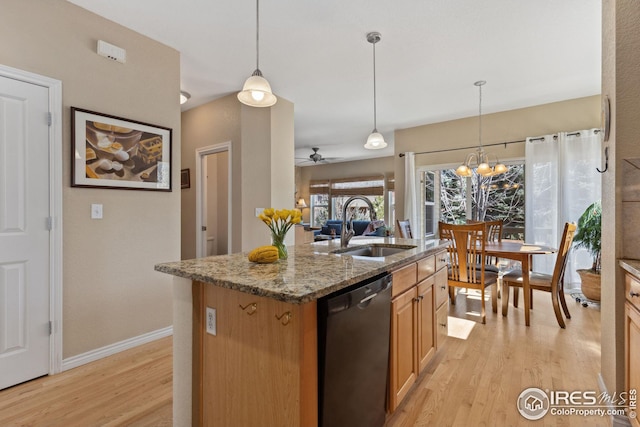 kitchen with light wood-type flooring, a center island with sink, a sink, light stone countertops, and dishwasher