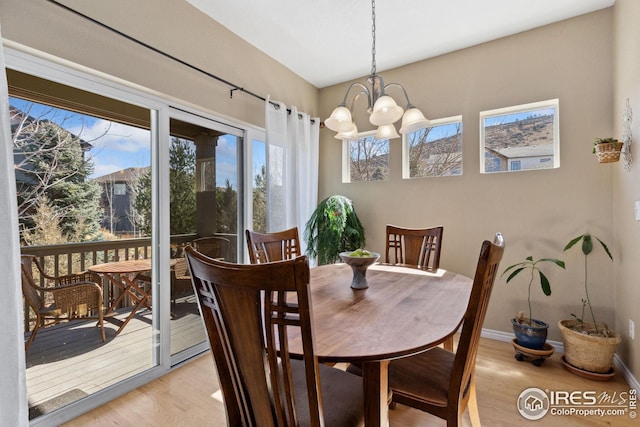 dining room featuring light wood finished floors, plenty of natural light, a chandelier, and baseboards