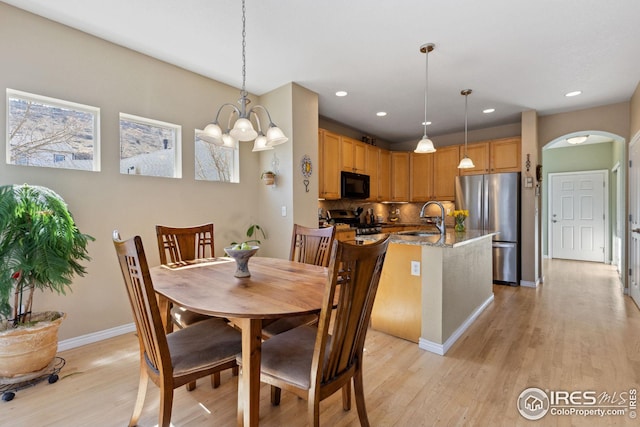 dining area featuring arched walkways, recessed lighting, light wood finished floors, and baseboards