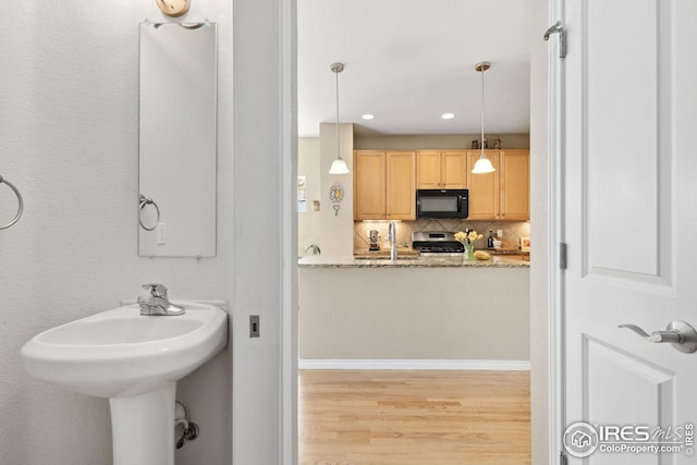 bathroom featuring a sink, tasteful backsplash, wood finished floors, and recessed lighting