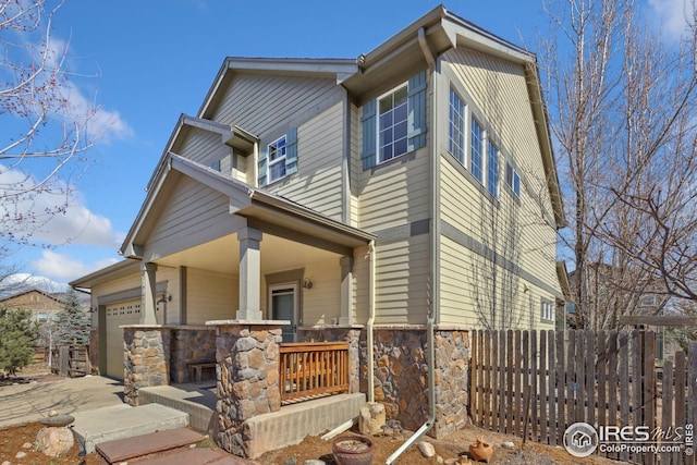 view of front of home with stone siding, a porch, an attached garage, and fence