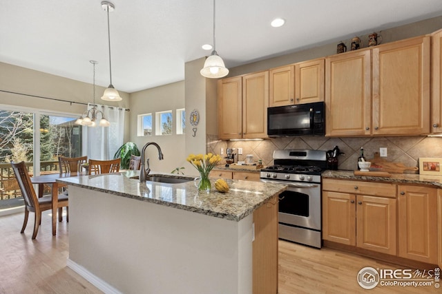 kitchen with light brown cabinetry, stainless steel range with gas cooktop, black microwave, and a sink