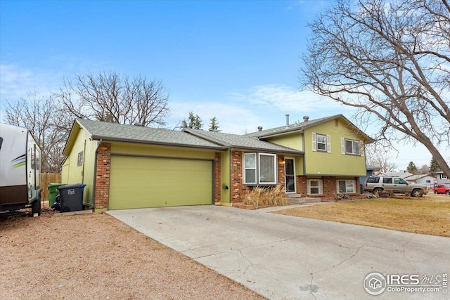 split level home featuring driveway, roof with shingles, a front lawn, a garage, and brick siding