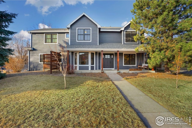 traditional home featuring a front lawn, stairway, and covered porch