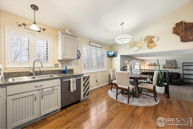 kitchen featuring hardwood / wood-style flooring, a sink, stainless steel dishwasher, dark countertops, and lofted ceiling