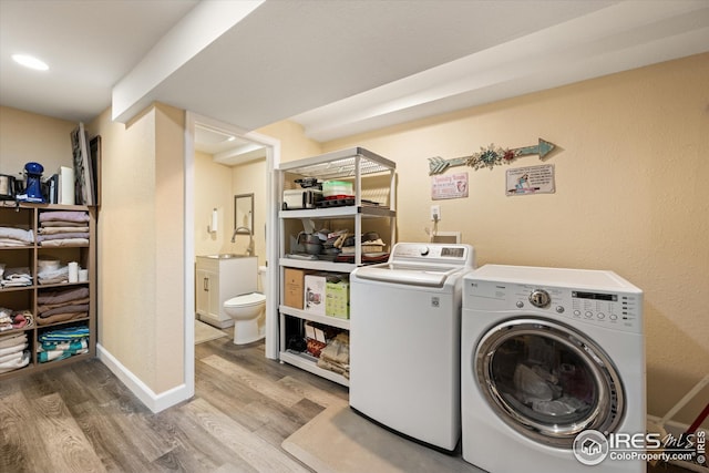 laundry area featuring a sink, wood finished floors, baseboards, and separate washer and dryer