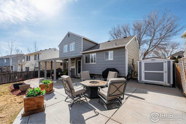 rear view of house featuring a patio, an outbuilding, a shed, a fenced backyard, and a fire pit