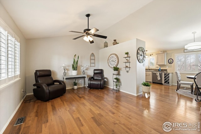 living area with light wood finished floors, visible vents, baseboards, vaulted ceiling, and a ceiling fan