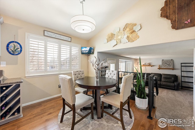 dining room featuring lofted ceiling, wood finished floors, and baseboards