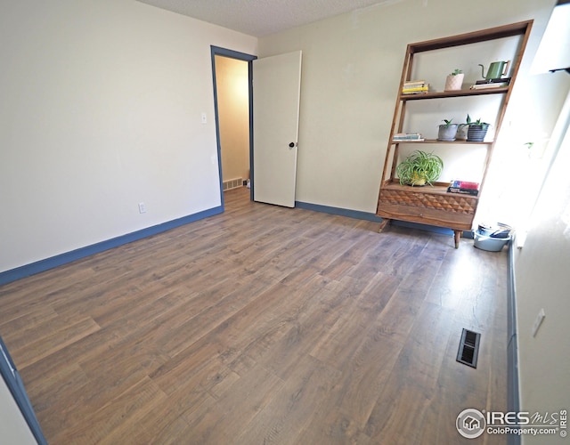 empty room featuring visible vents, baseboards, and wood finished floors