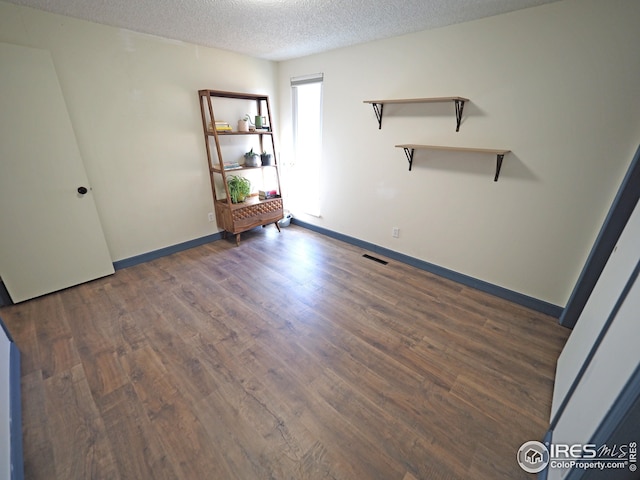 unfurnished bedroom featuring baseboards, wood finished floors, visible vents, and a textured ceiling