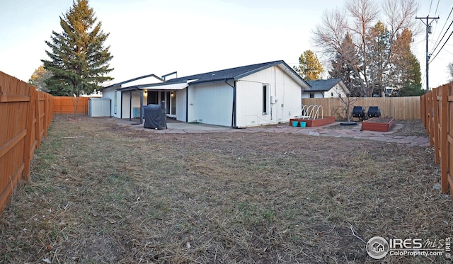 back of property featuring a yard, a fenced backyard, and a patio area