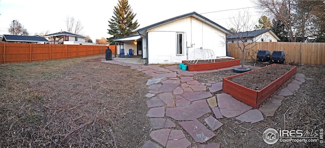 rear view of property with a fenced backyard, a patio, and a vegetable garden