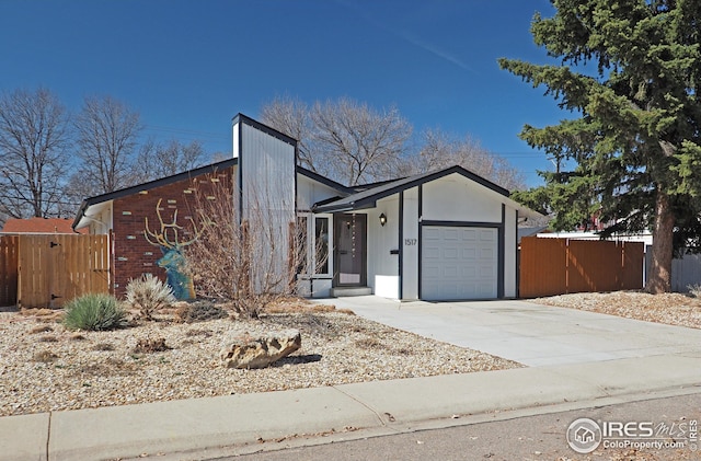 view of front of house with concrete driveway, an attached garage, and fence