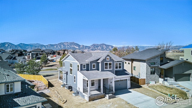 view of front facade with fence, driveway, an attached garage, a residential view, and a mountain view