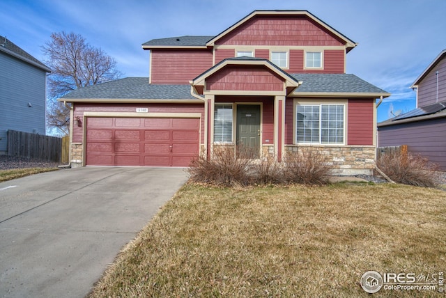 view of front of house with driveway, stone siding, fence, roof with shingles, and an attached garage